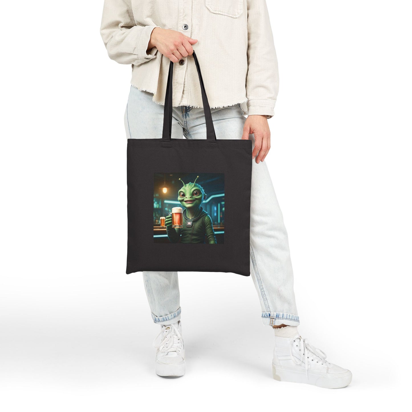 Alien woman drinking a Beer in a pub at night. The alien Is featured on a black color Canvas tote bag. Woman style views.
