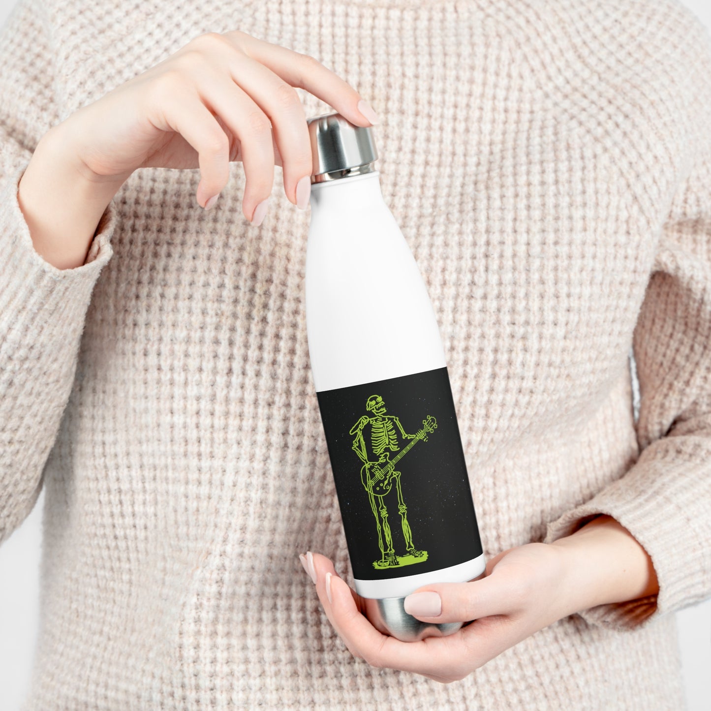 Person holding a white insulated water bottle with a original bass player metal skeleton fluo original design on a black background