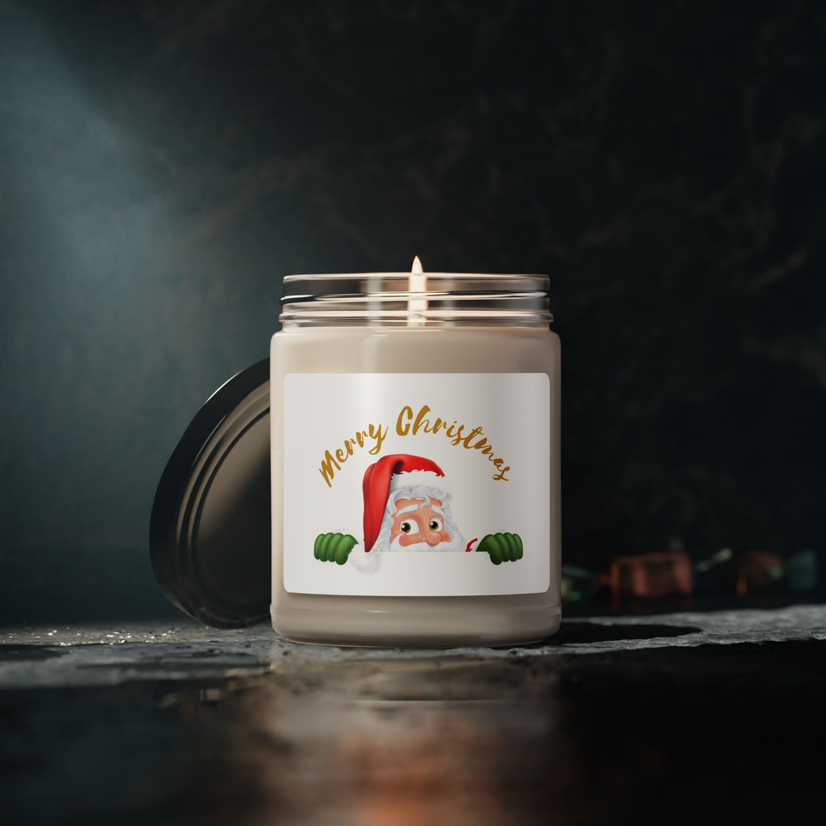 Glowing Christmas soy candle with peeking Santa Claus artwork sitting on a dark wooden surface with a warm cozy evening atmosphere.