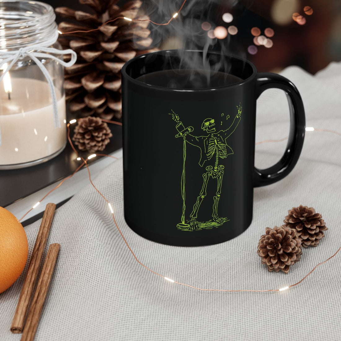 Black ceramic mug with green fluo skeleton rock singer design steaming on a cozy table setup