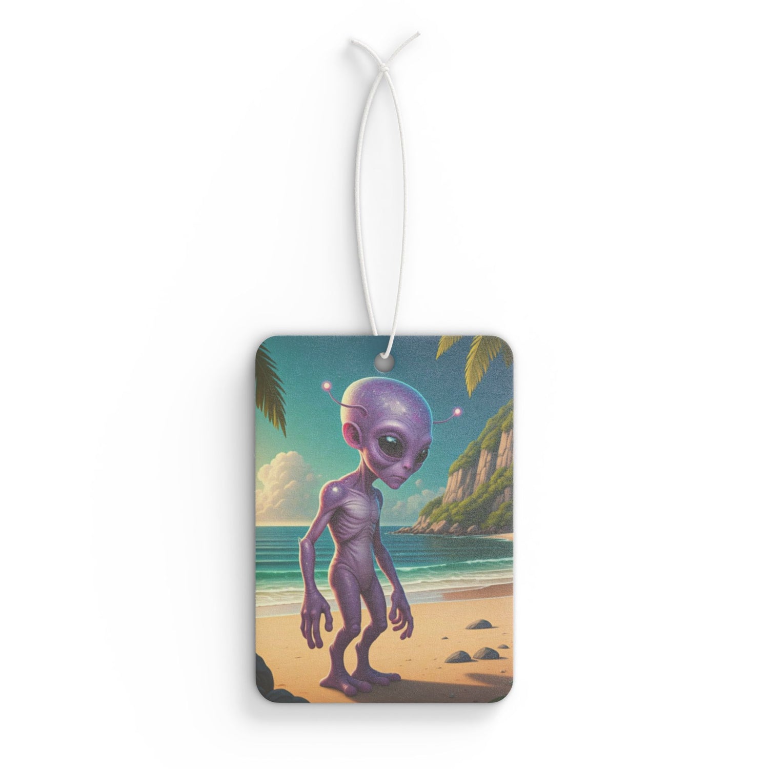 Rectangular car air freshener showing a tall, purple alien standing on a sandy tropical beach with ocean waves and green palm leaves overhead.