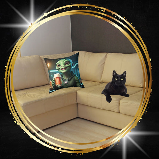 Decorative throw pillow featuring a funny alien holding a beer mug graphic from From Space Store on a beige sofa next to a black cat.