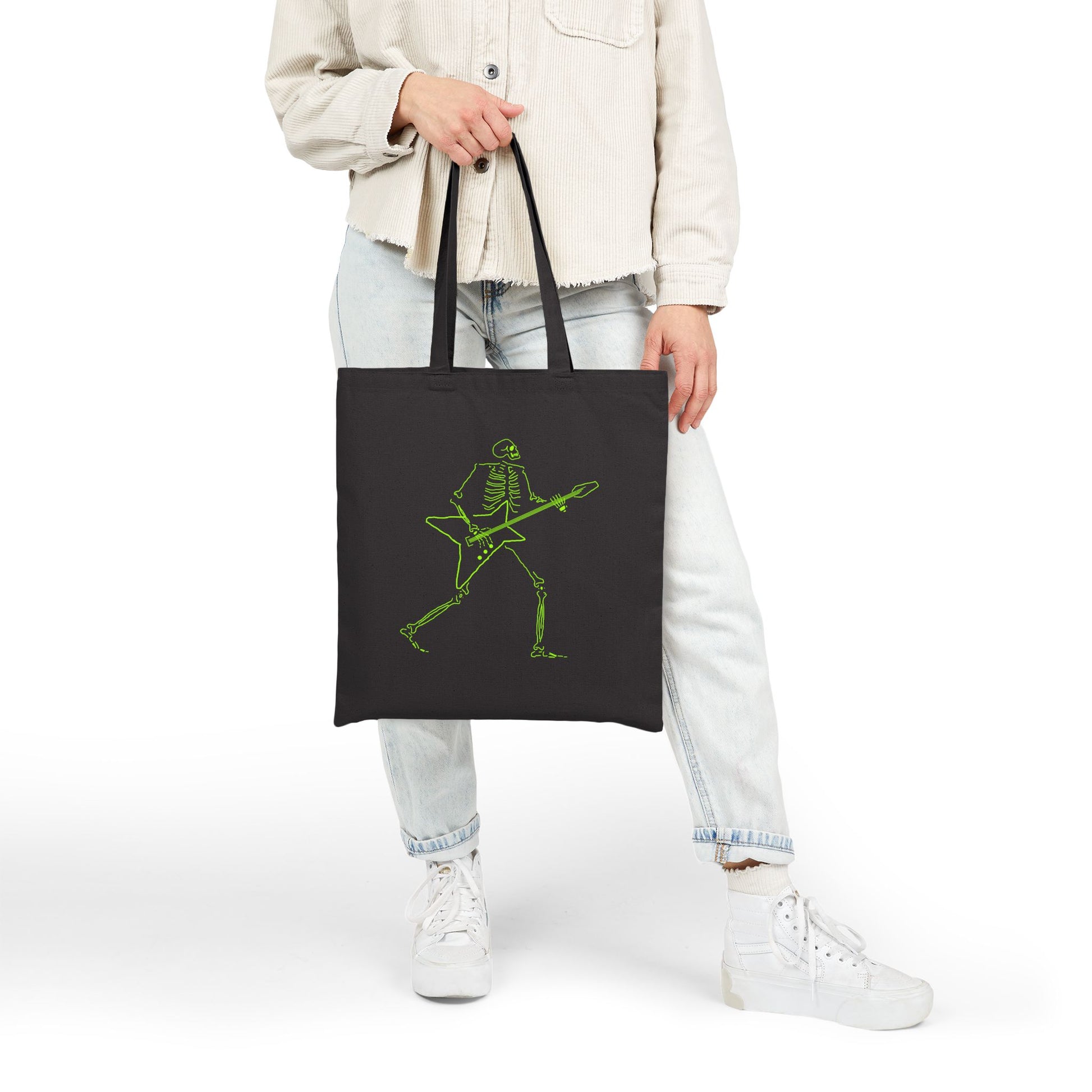 Person holding a black tote bag with a green skeleton metal guitarist unique design