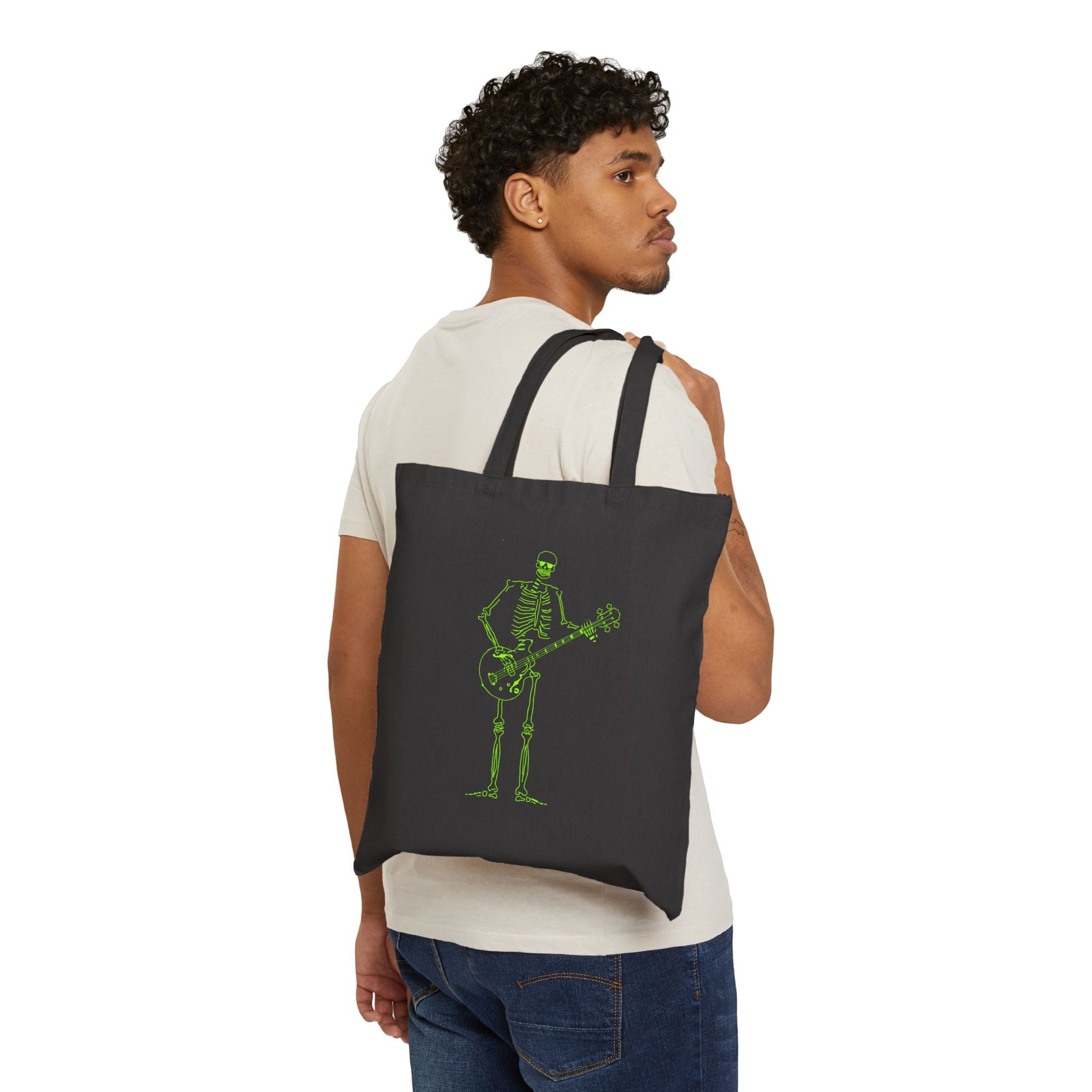 Person wearing a black tote bag with original a green skeleton playing guitar design