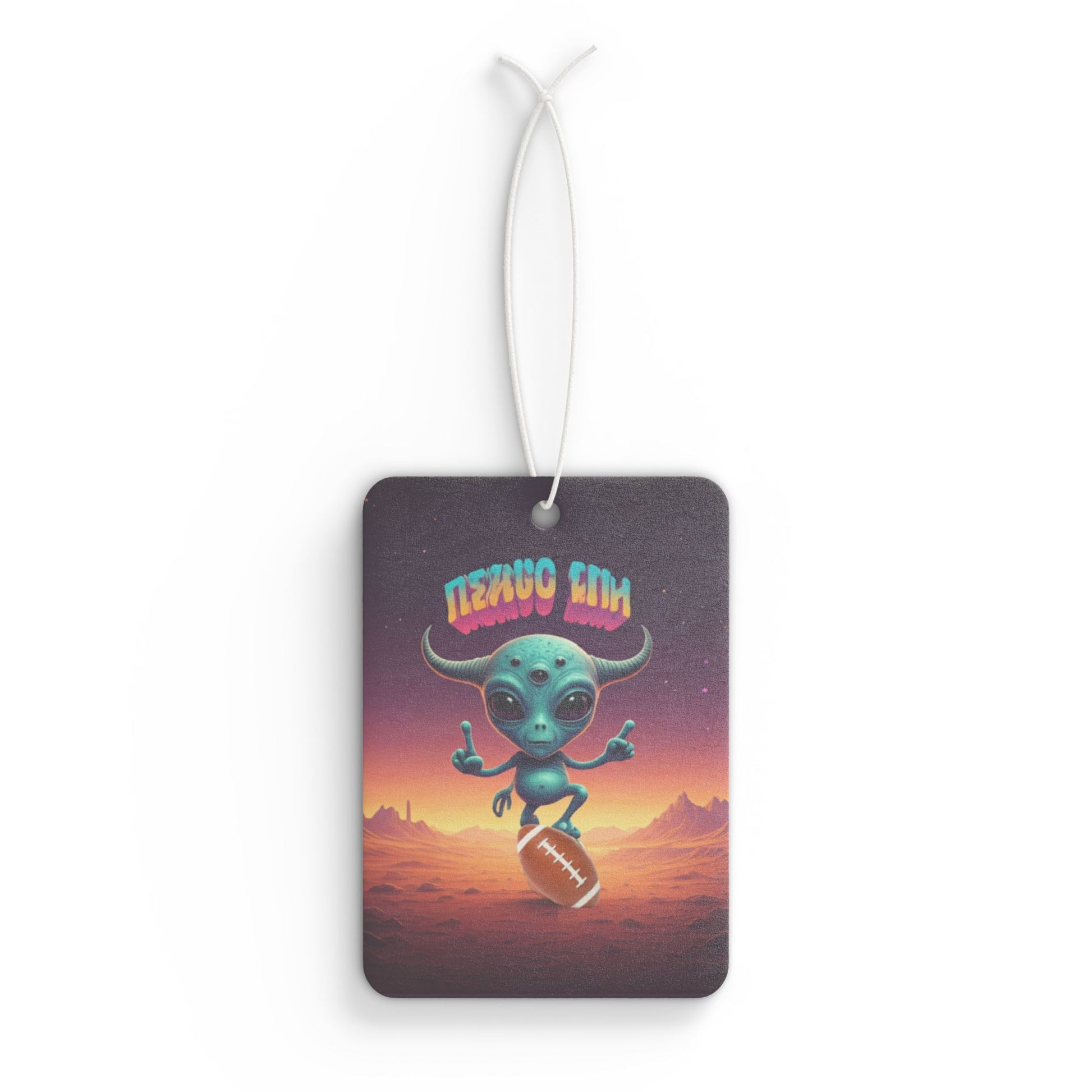 Image of a small, three-eyed blue alien with horns balancing on an American football against a purple and orange cosmic desert background.