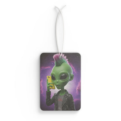 Rectangular car air freshener showing a green alien with a pink and purple mohawk wearing a leather jacket and talking on a yellow mobile phone against a starry galaxy background.