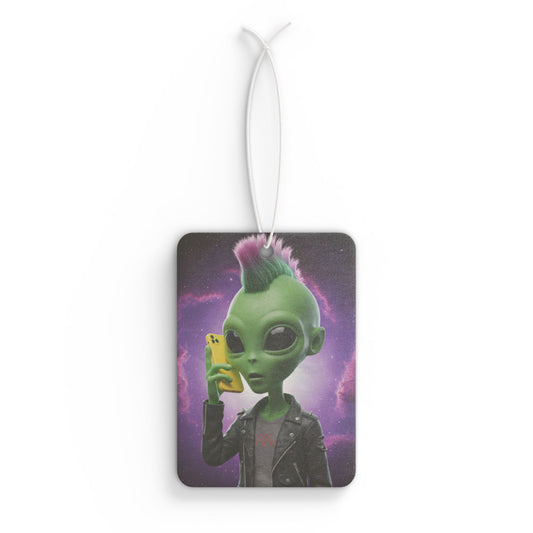 Rectangular car air freshener showing a green alien with a pink and purple mohawk wearing a leather jacket and talking on a yellow mobile phone against a starry galaxy background.