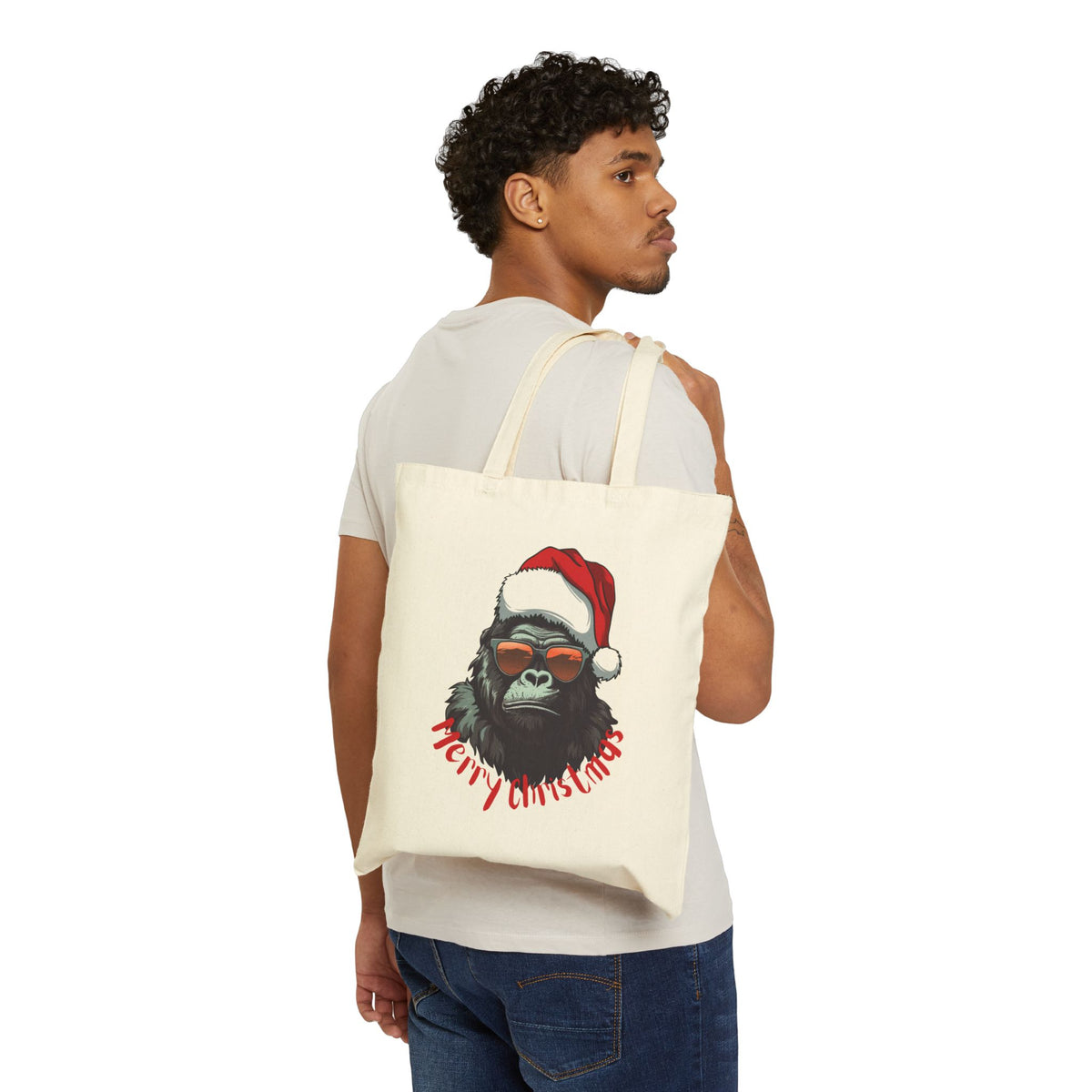 Man wearing white t-shirt holding a badass santa gorilla merry christmas canvas tote bag for alternative holiday shopping
