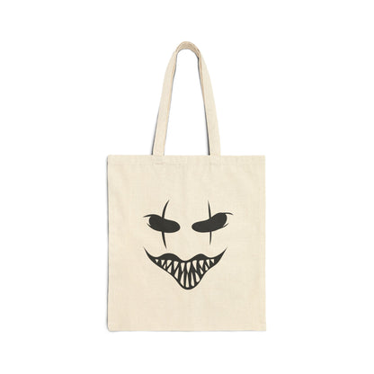 Beige tote bag with a black face design on a white background