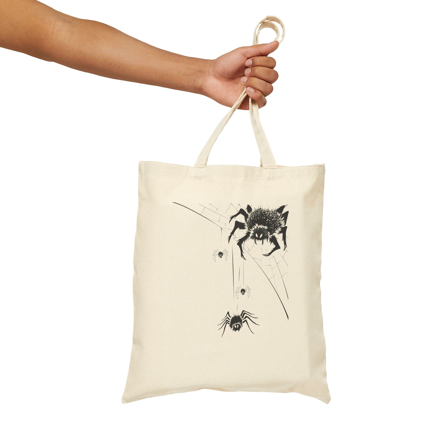 Tote bag with spider design held by a hand on a white background