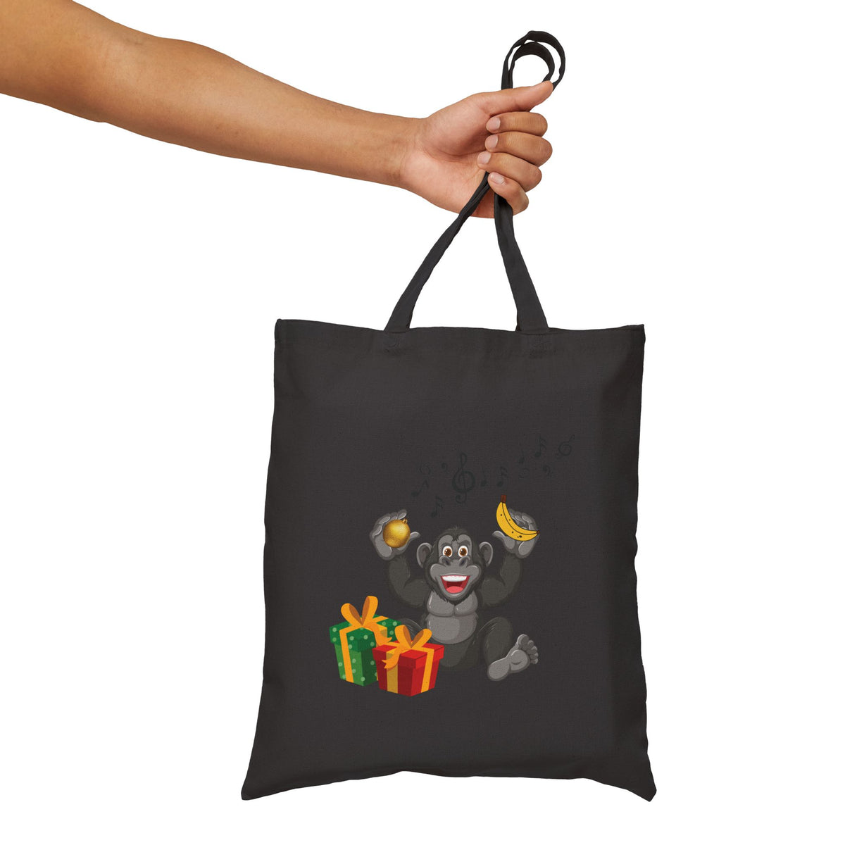 Black canvas tote bag held in hand featuring a cute musical gorilla graphic with Christmas gifts for fun holiday travel and errands.