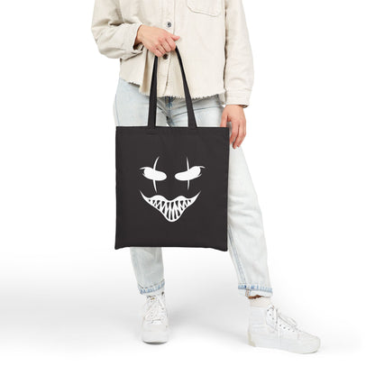 Person holding a black tote bag with a white face design on a white background