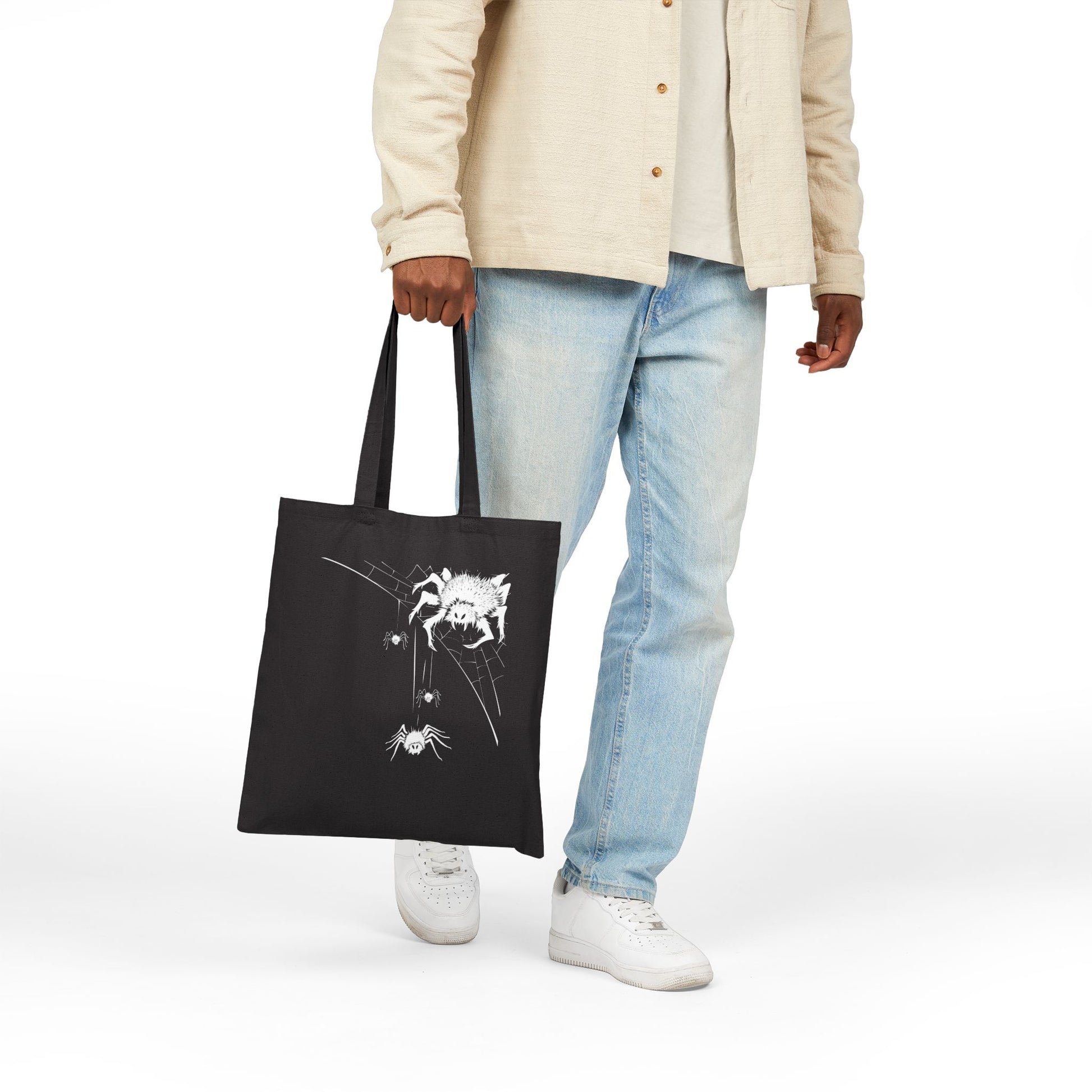 Young man holding a black tote bag with a originale spider design
