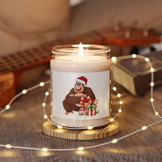 Lit soy wax glass jar Christmas candle featuring a funny gorilla wearing a Santa hat with holiday gifts, glowing among warm fairy lights on a wooden table.