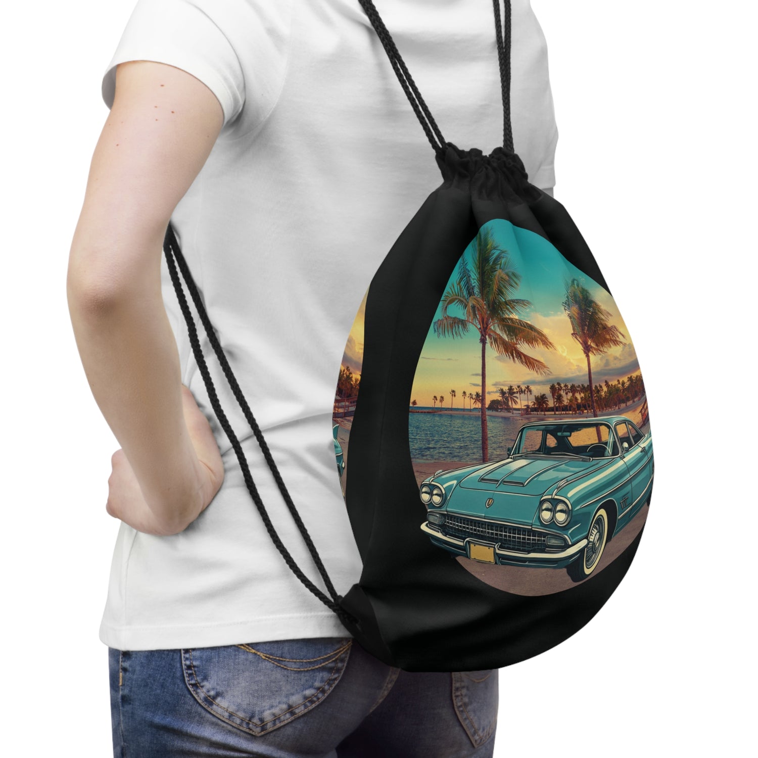 Drawstring bag with vintage cadillac car and beach design held by a person wearing a white t-shirt