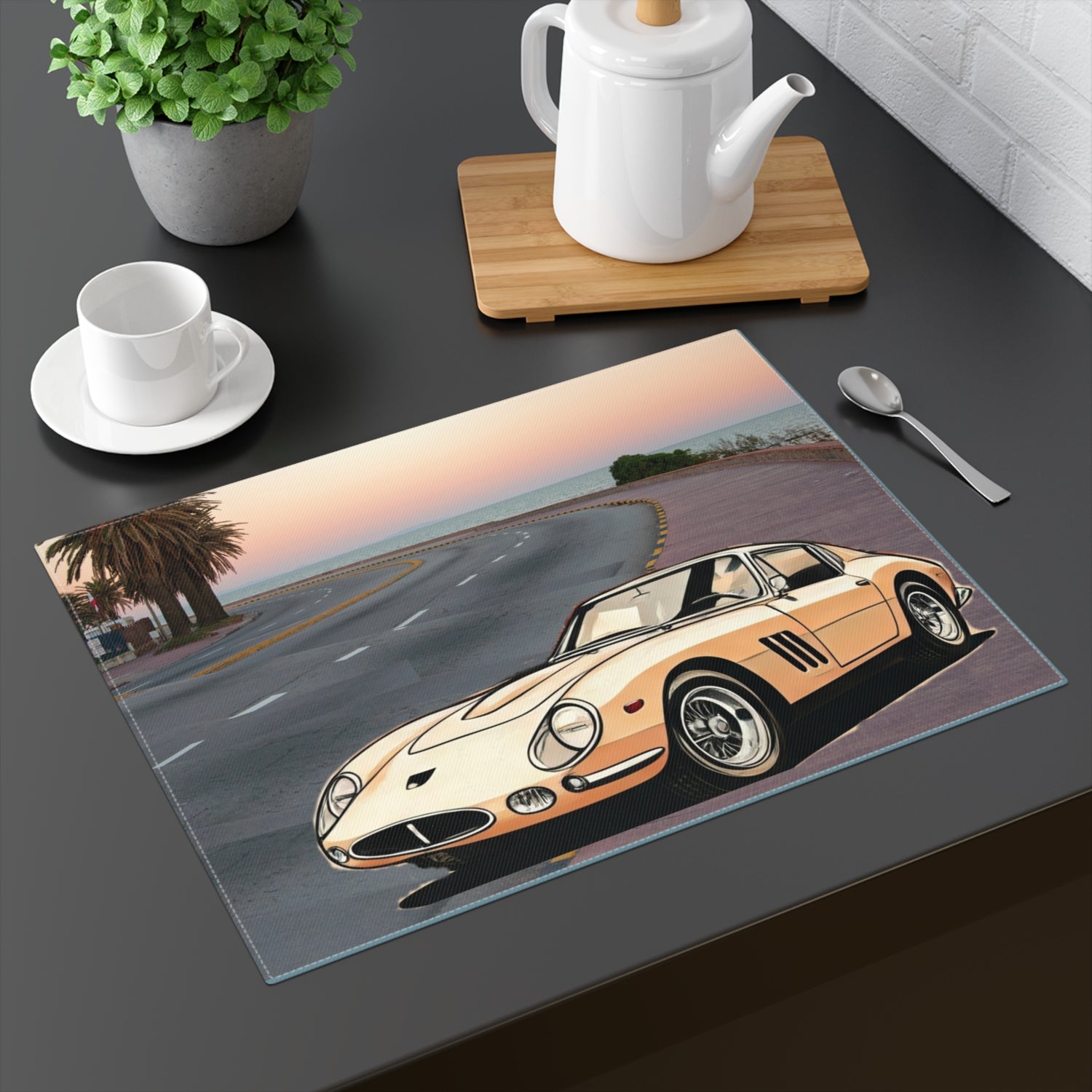 Classic Ferrari 275 GTB driving on a winding coastal road at sunset on a placemat.