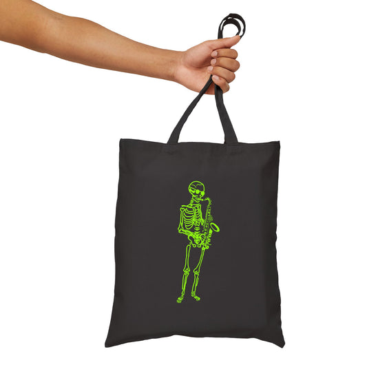 Black tote bag with a green fluo skeleton playing sax design held by a hand 