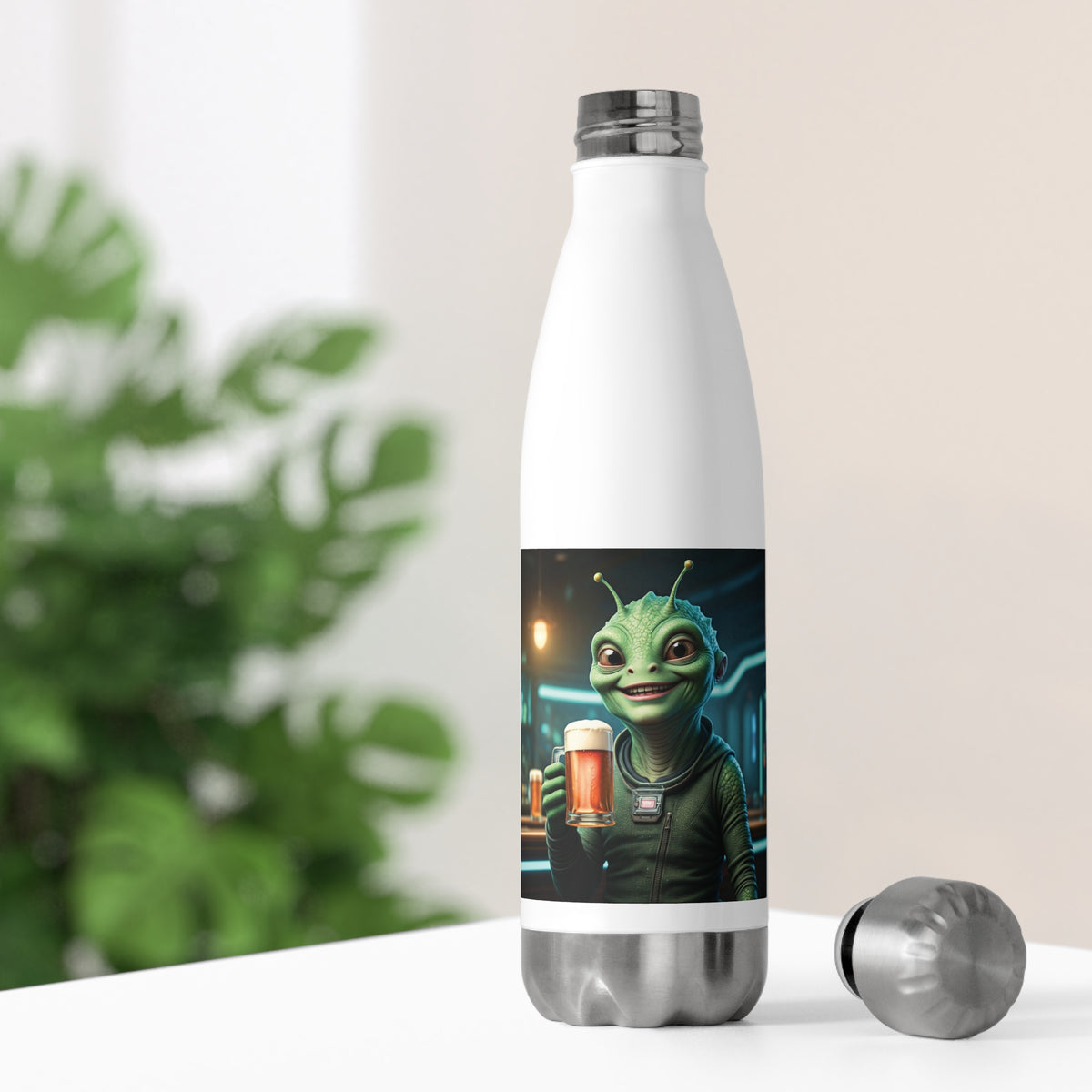 White thermal travel water bottle sitting on a desk with its stainless steel cap off, showing a hilarious alien holding a beer mug for home and office hydration.