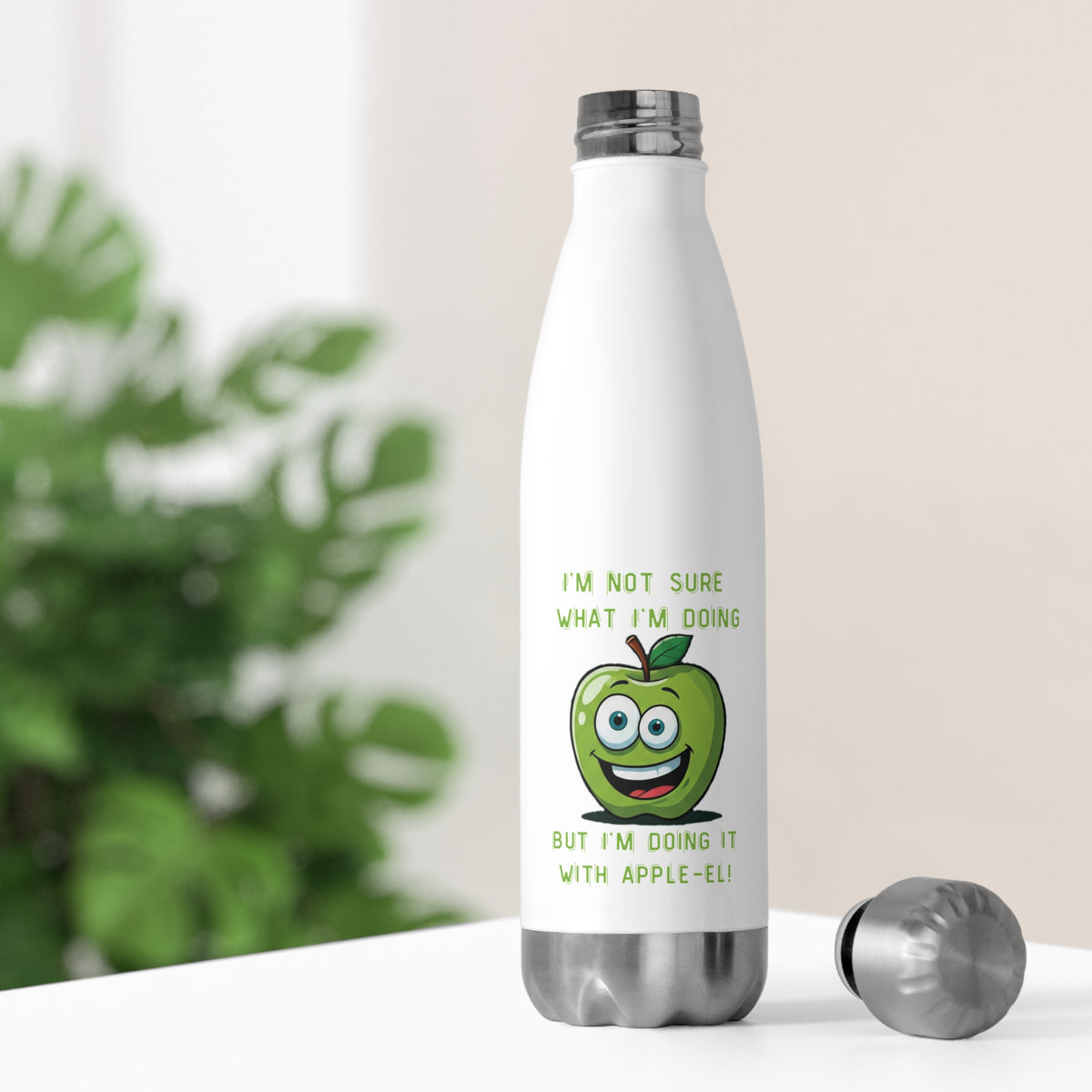 White thermal travel water bottle sitting on a bright desk with its stainless steel cap off, showing a smiling green apple illustration for home office hydration.