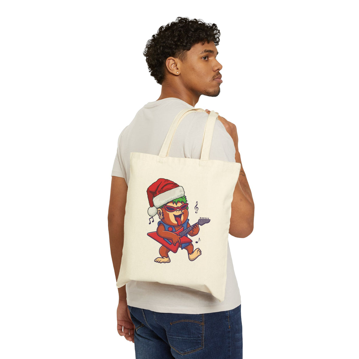 Man wearing white t-shirt holding a funny rockstar santa monkey canvas tote bag for holiday gift shopping