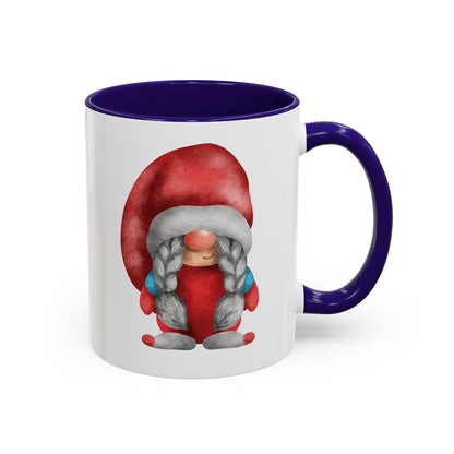 Red gnome navy mug with braids next to a cozy knit sweater and a book)