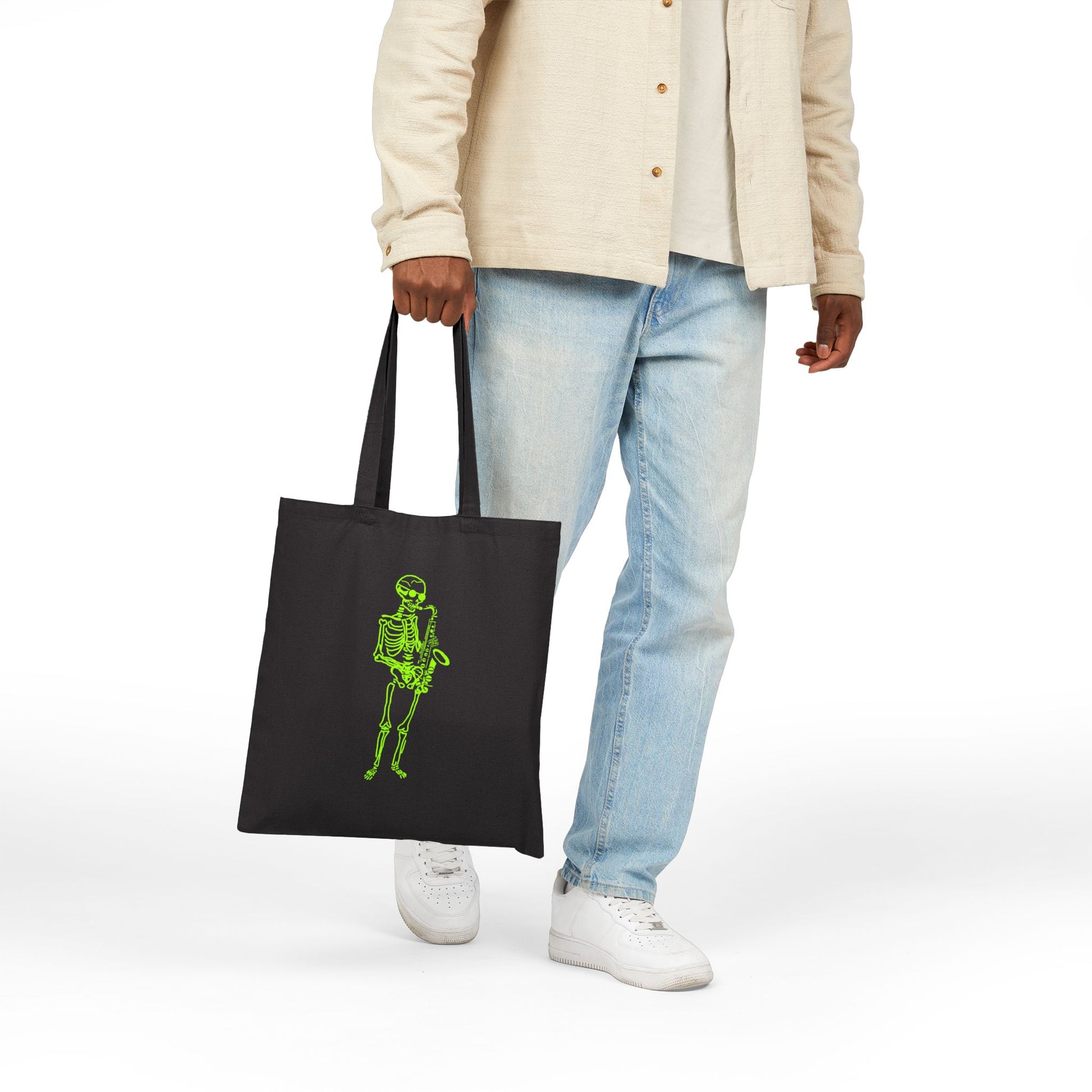 Person holding a black tote bag with a green skeleton design playing sax