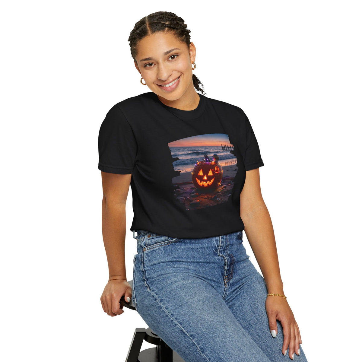 Woman wearing the From Space Store Halloween beach pumpkin graphic t-shirt and blue jeans while sitting.