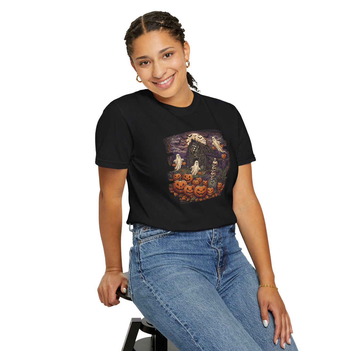Woman wearing the From Space Store Halloween haunted house graphic t-shirt and blue jeans while sitting.