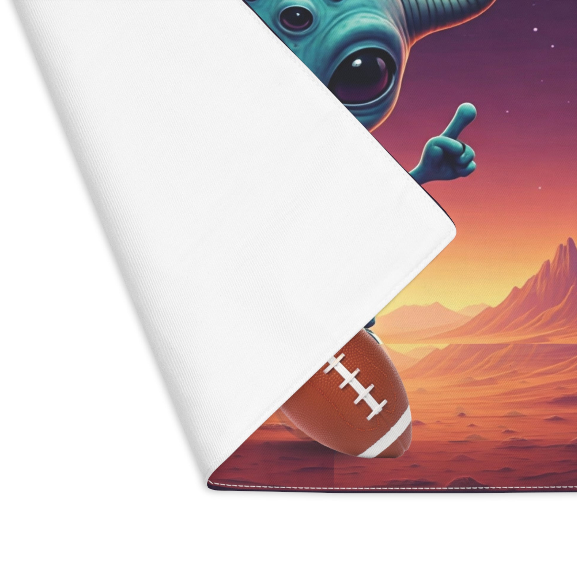 Roll of placemat with a space-themed design featuring an alien and football on a desert landscape.