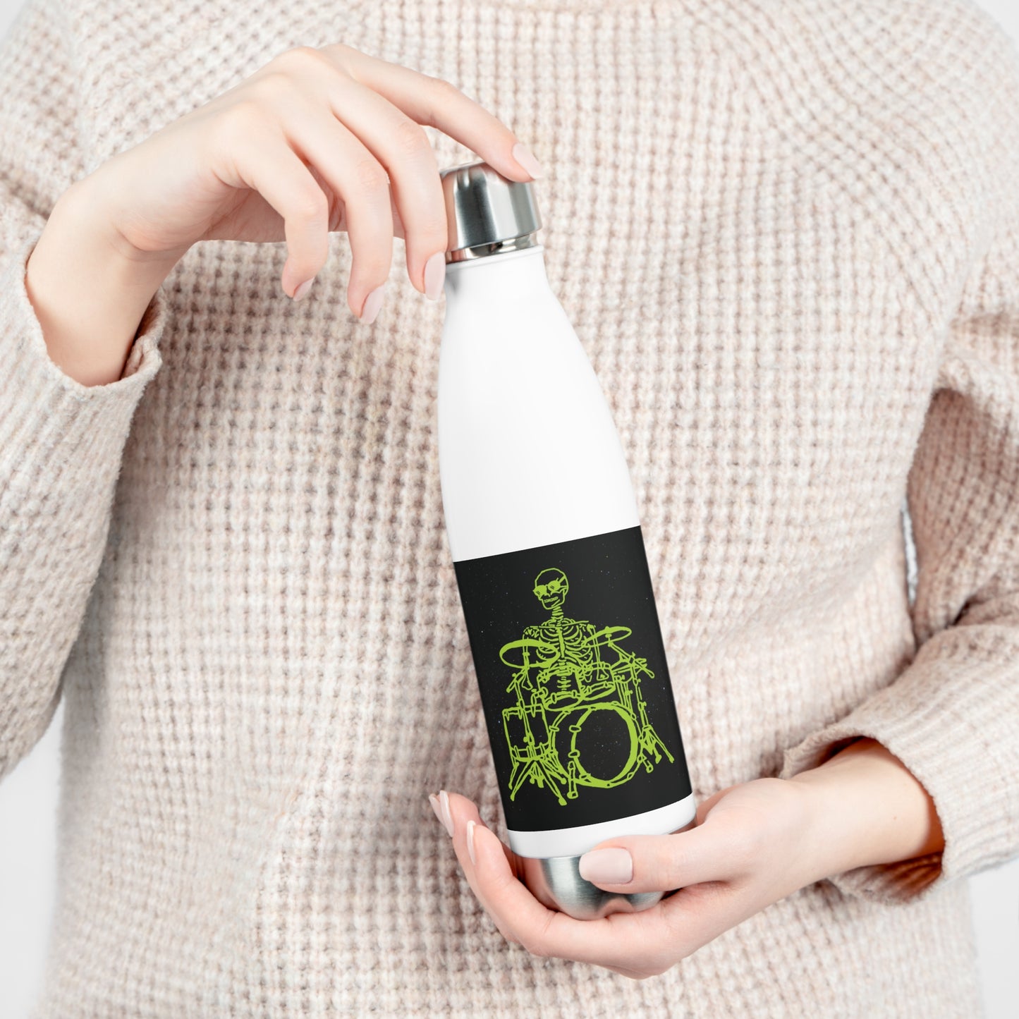 Person holding a white insulated water bottle with a original drums player metal skeleton fluo original design on a black background
