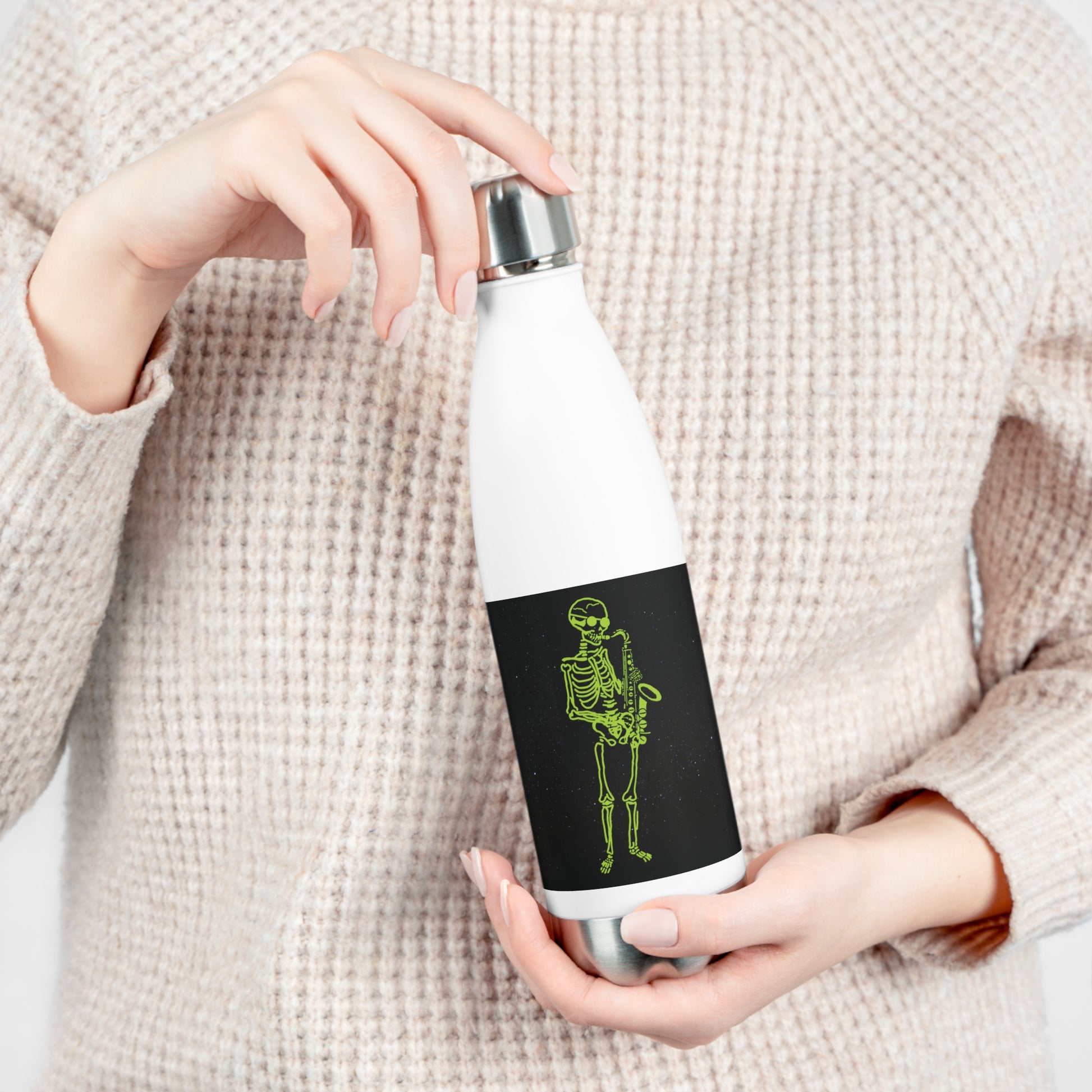 Person holding a white water bottle with a original sax player metal skeleton fluo original design on a black background