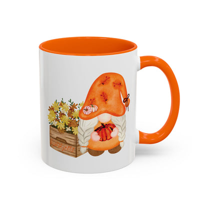 White and orange ceramic coffee mug with a colorful graphic of a mysterious gnome surrounded by autumn leaves and mushrooms.