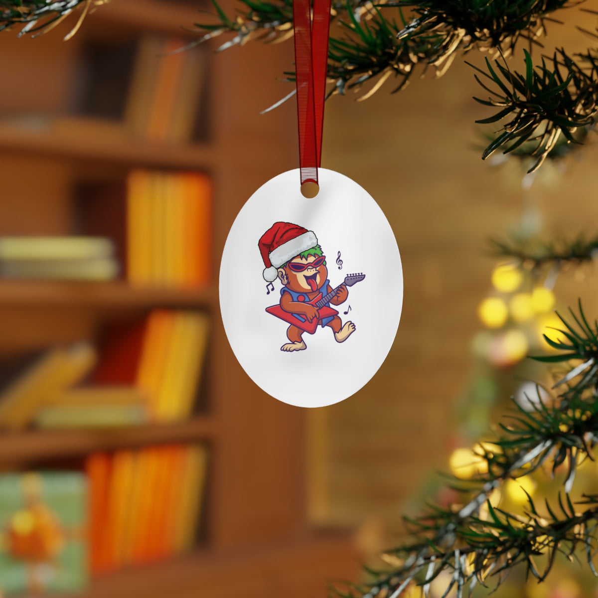 Oval Christmas tree ornament featuring a rocking Santa hat gorilla jamming on an electric guitar displayed on an evergreen pine branch.