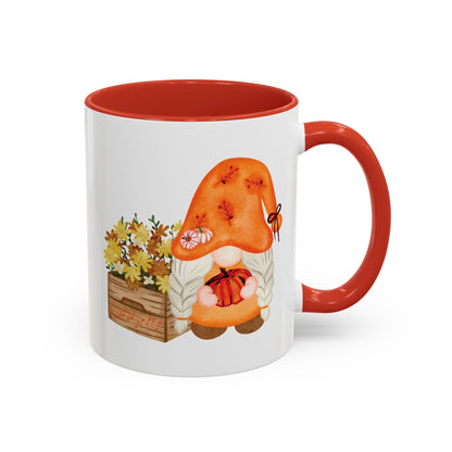 White and red ceramic coffee mug with a colorful graphic of a mysterious gnome surrounded by autumn leaves and mushrooms.