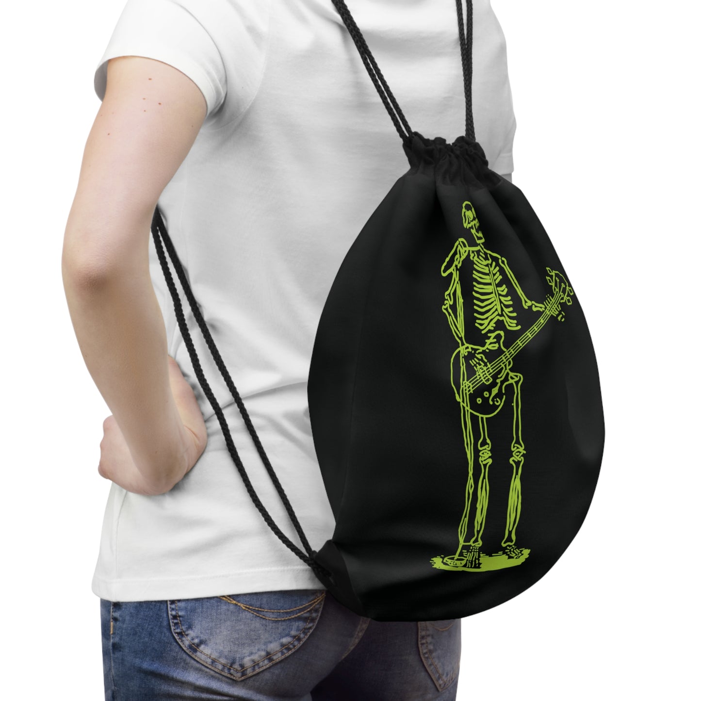 Person holding a black drawstring bag with a green skeleton playing guitar unique design.