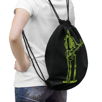Person holding a black drawstring bag with a green skeleton playing guitar unique design.