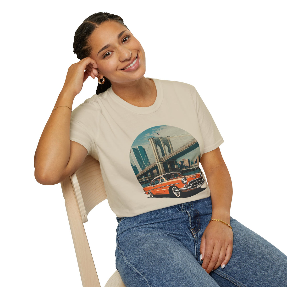 Woman sitting wearing a vintage cars graphic t-shirt featuring a classic vintage car in front of the Brooklyn Bridge