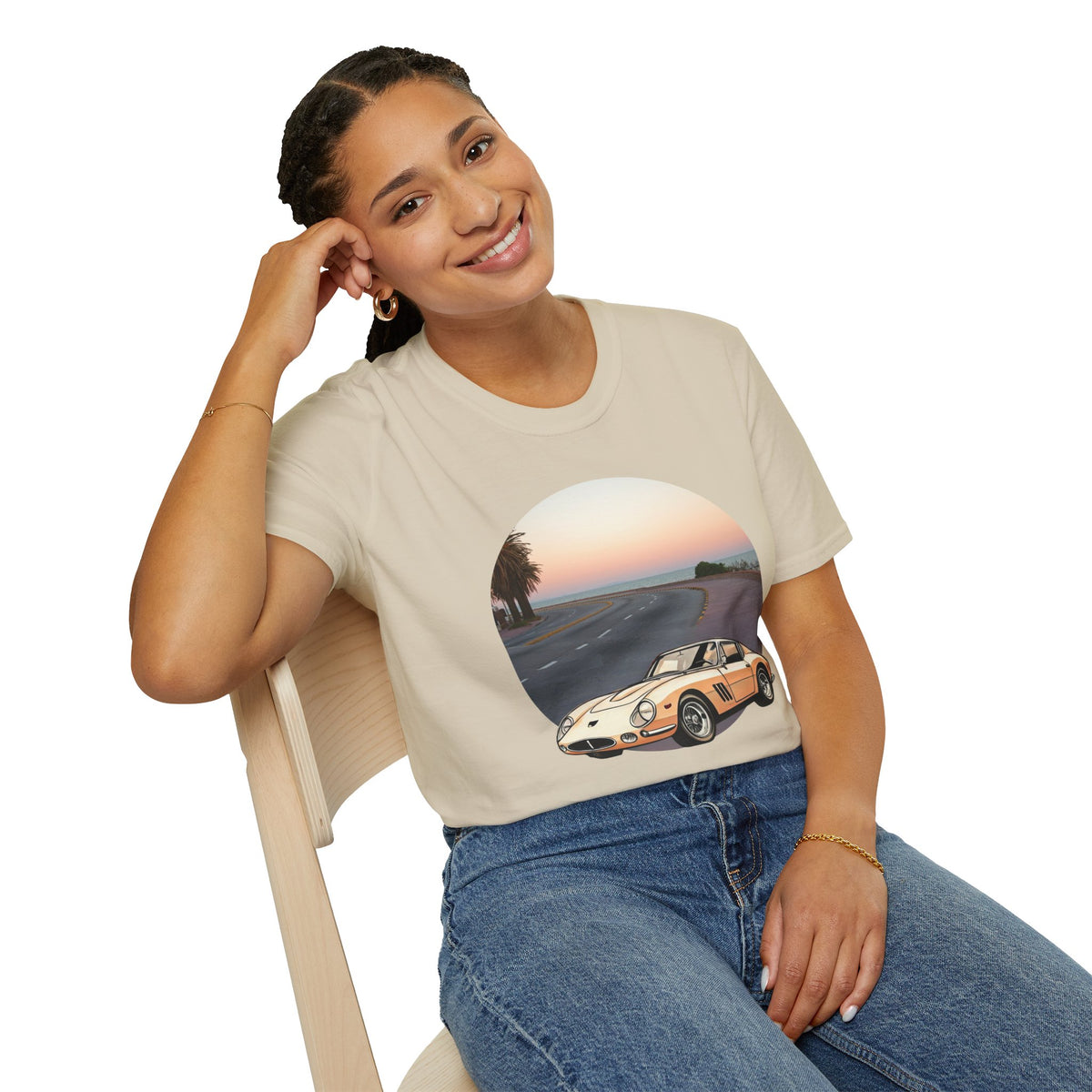 Woman sitting wearing a vintage cars graphic t-shirt featuring a classic retro sports car on a coastal road.