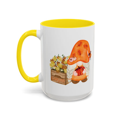 White and yellow ceramic coffee cup with a colorful graphic of a mysterious gnome surrounded by autumn leaves and mushrooms.